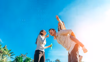 A young family blowing bubbles under a clear blue sky